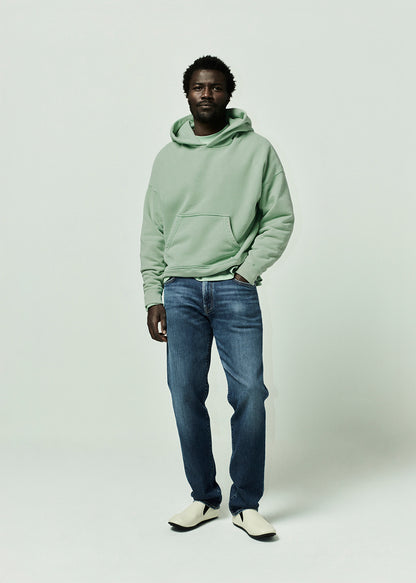 Person wearing green hoodie paired with blue jeans