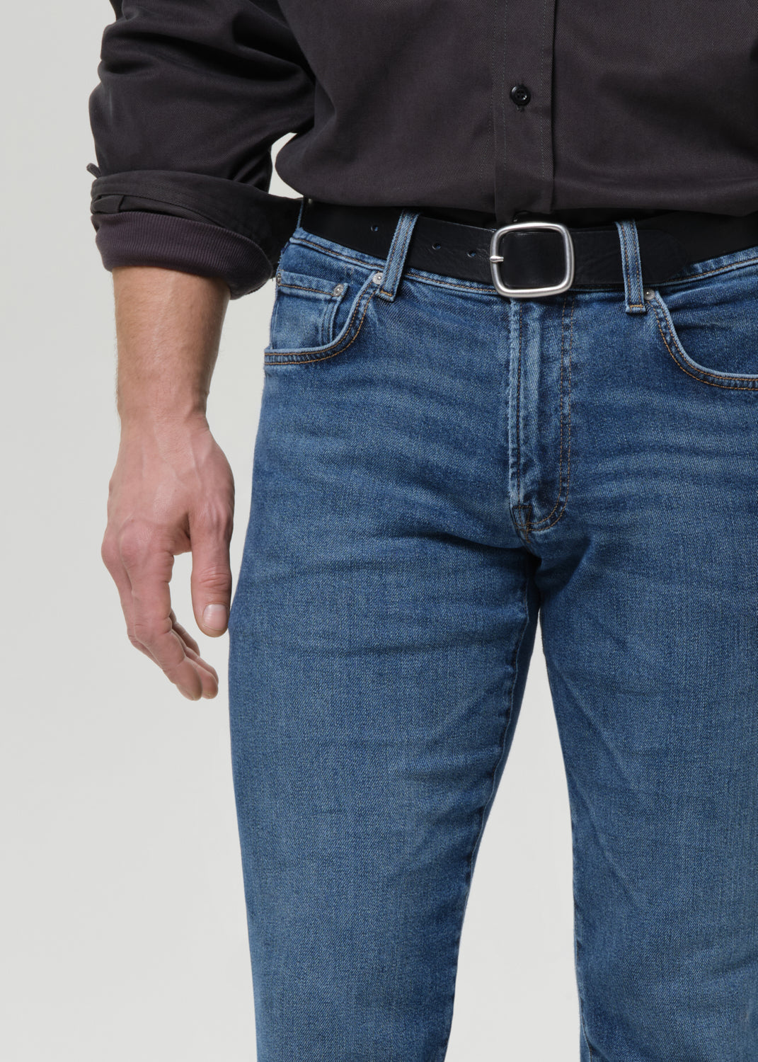 Close-up of medium blue straight leg jeans on a grey background.