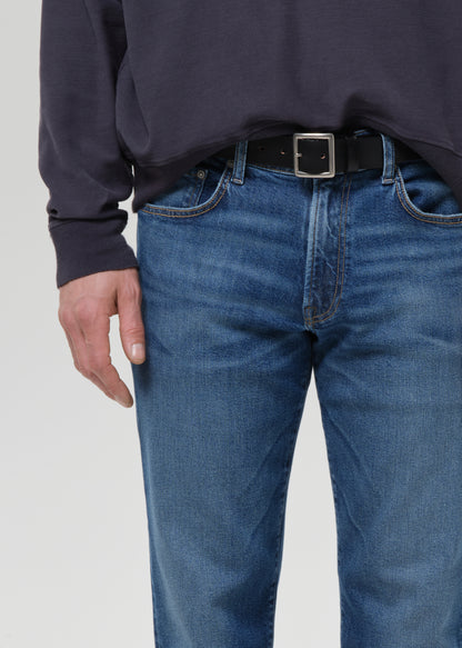 Person wearing blue jeans and a dark sweater on a grey background