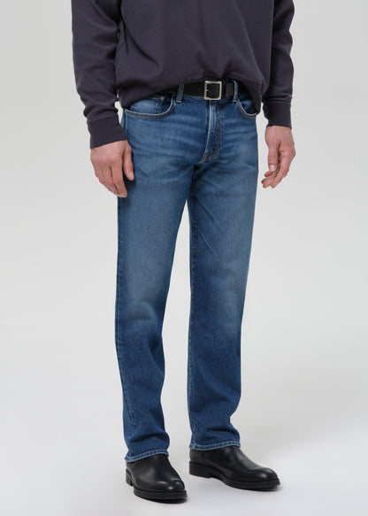 Person wearing blue jeans and a dark shirt on a grey background