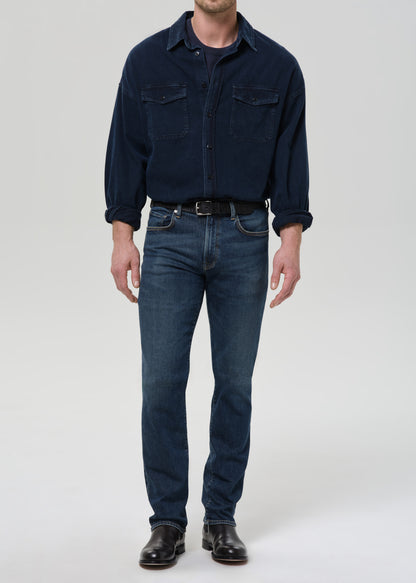 Person wearing a navy blue shirt and jeans on a grey background