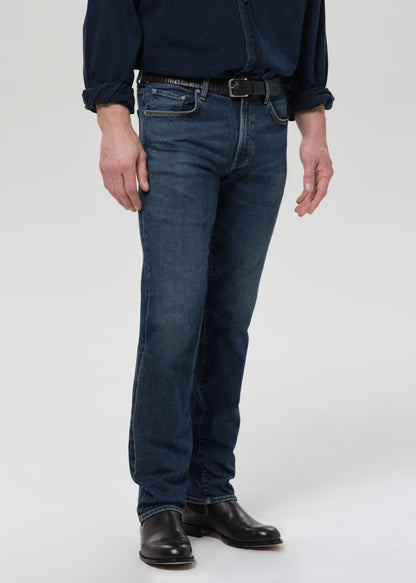 Person wearing blue jeans and a dark shirt on a grey background