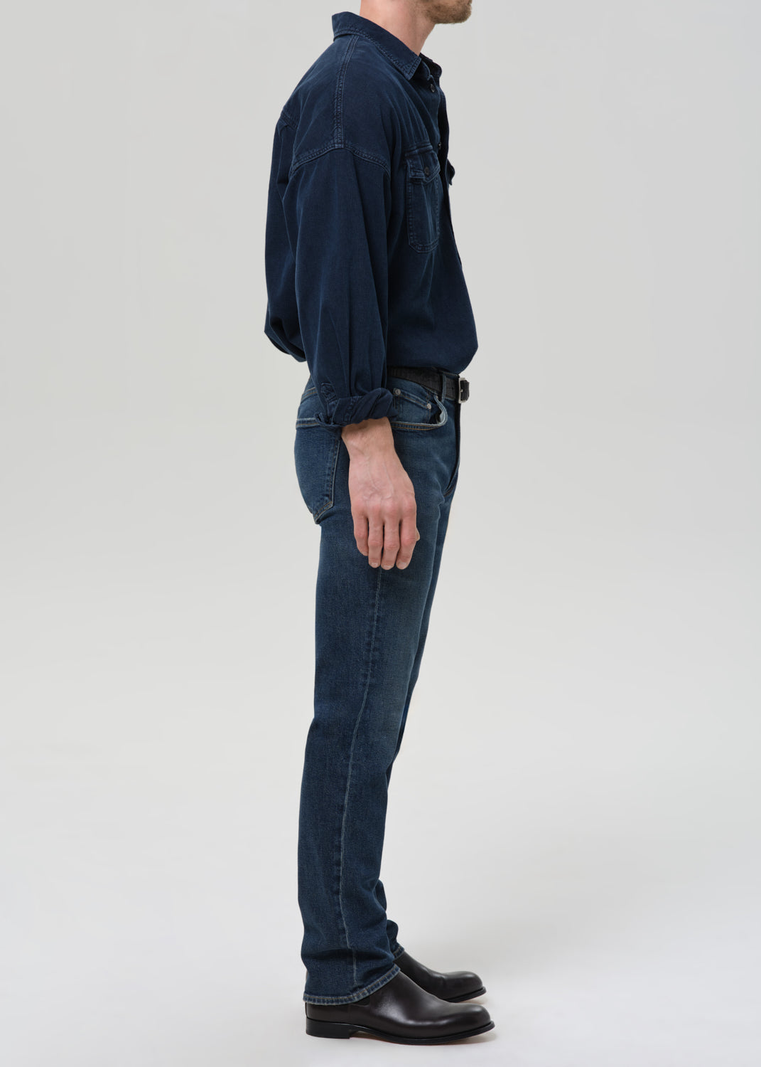 Person wearing a dark blue shirt and jeans on a grey background