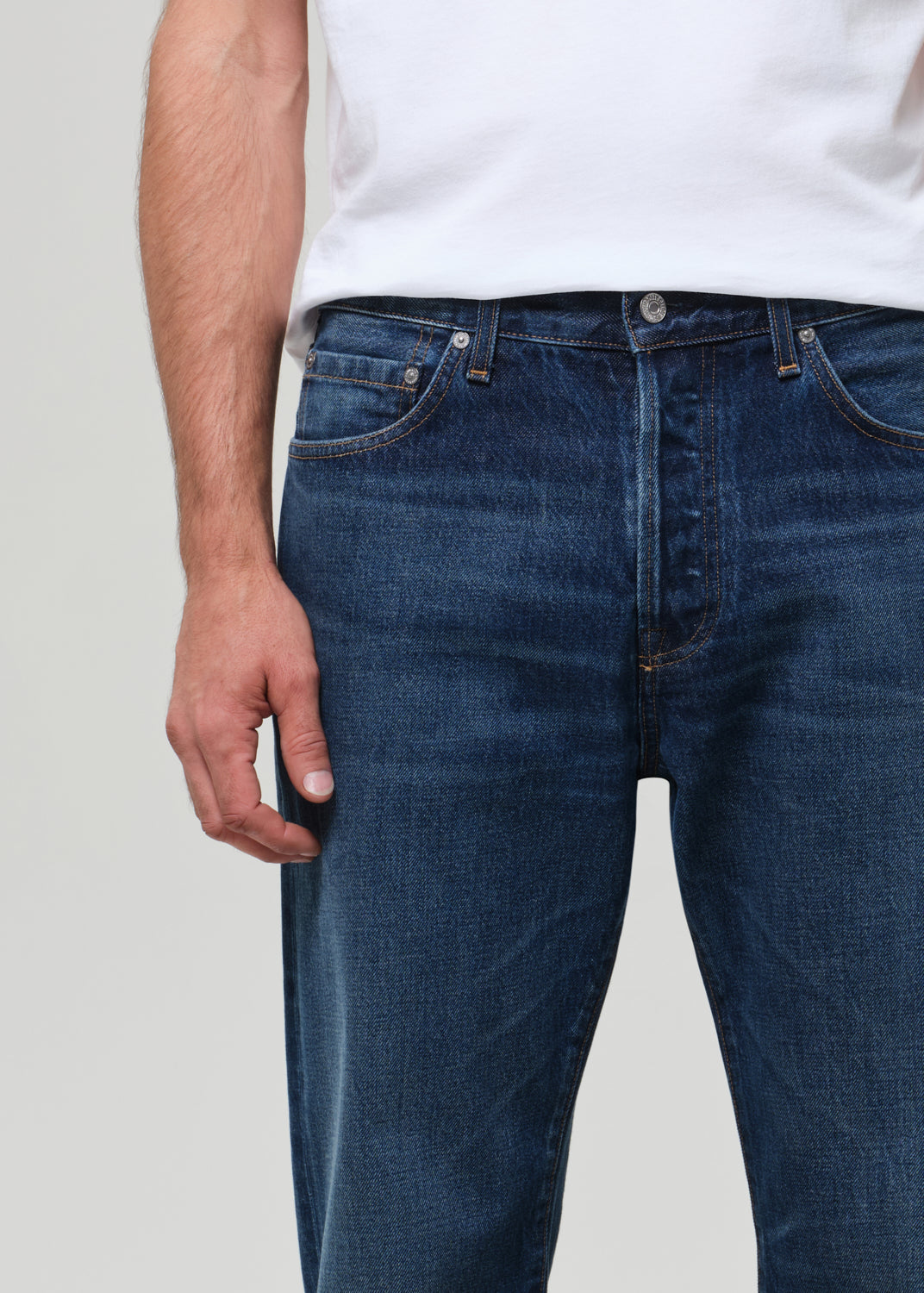 Person wearing a white t-shirt and blue jeans on a plain background
