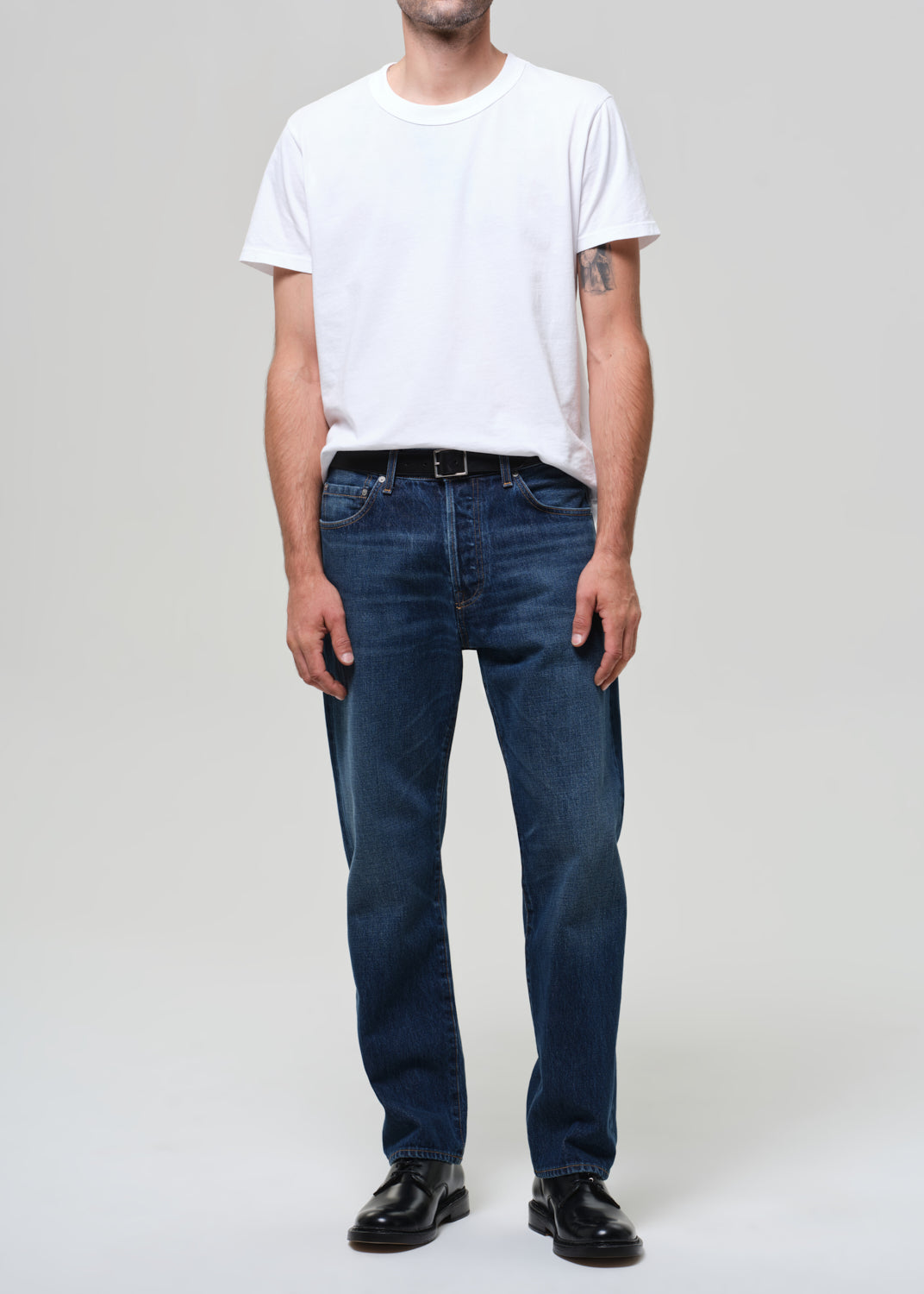 Person wearing a white t-shirt and blue jeans on a plain background