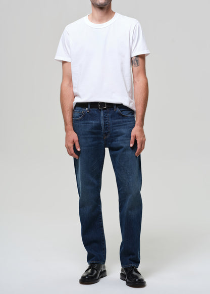 Person wearing a white t-shirt and blue jeans on a plain background