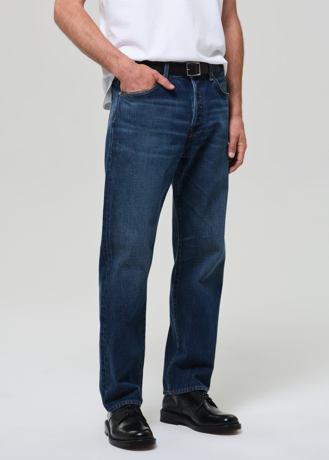 Person wearing a white t-shirt and blue jeans on a plain background