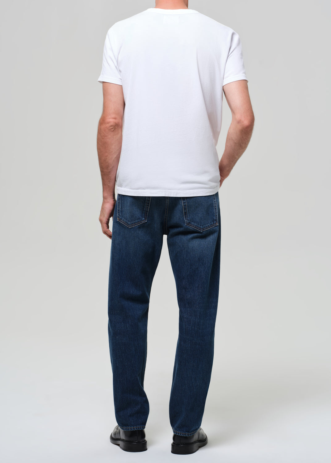 Person wearing a white t-shirt and blue jeans on a plain background