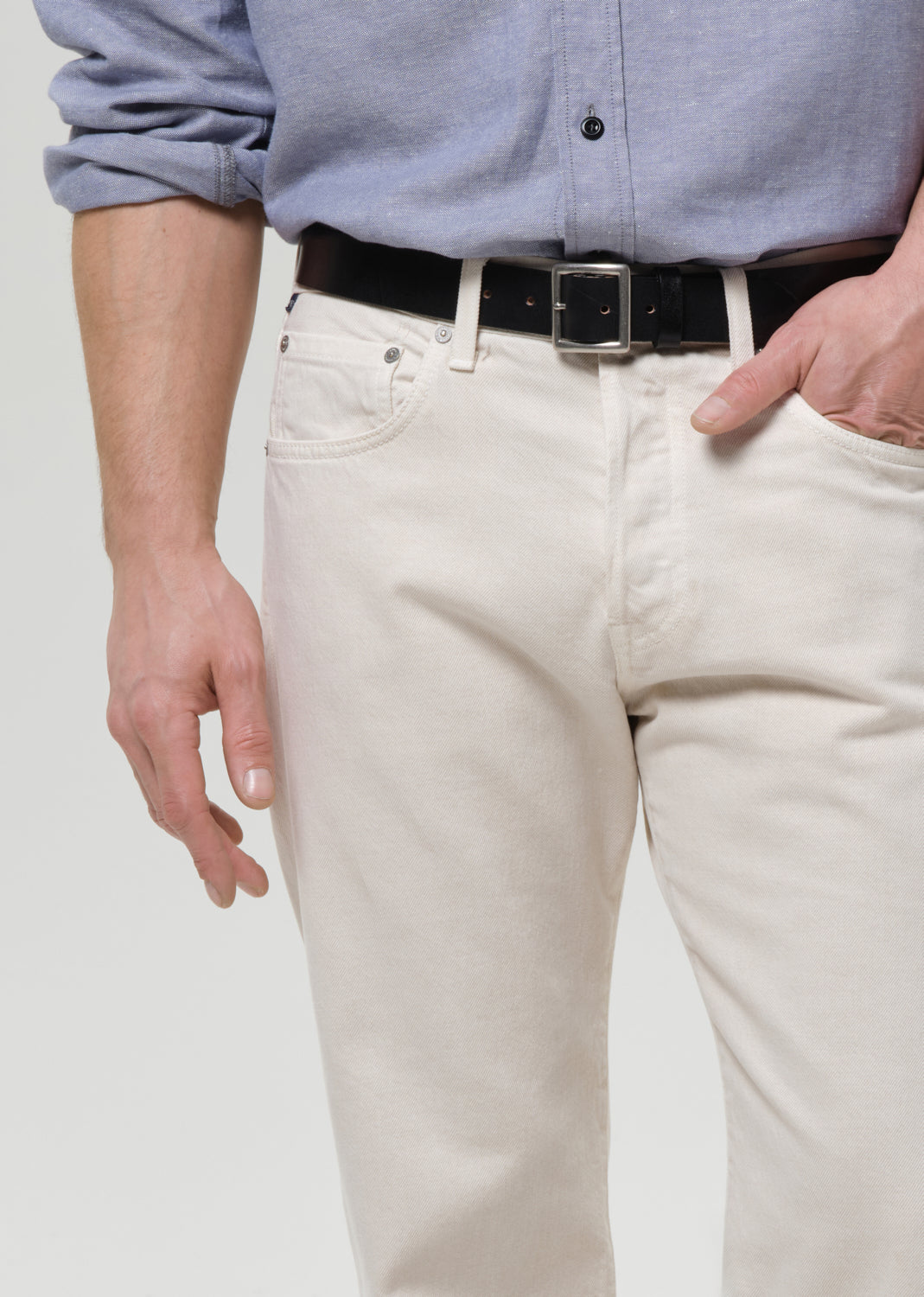 Person wearing a light blue shirt and beige pants with a black belt.