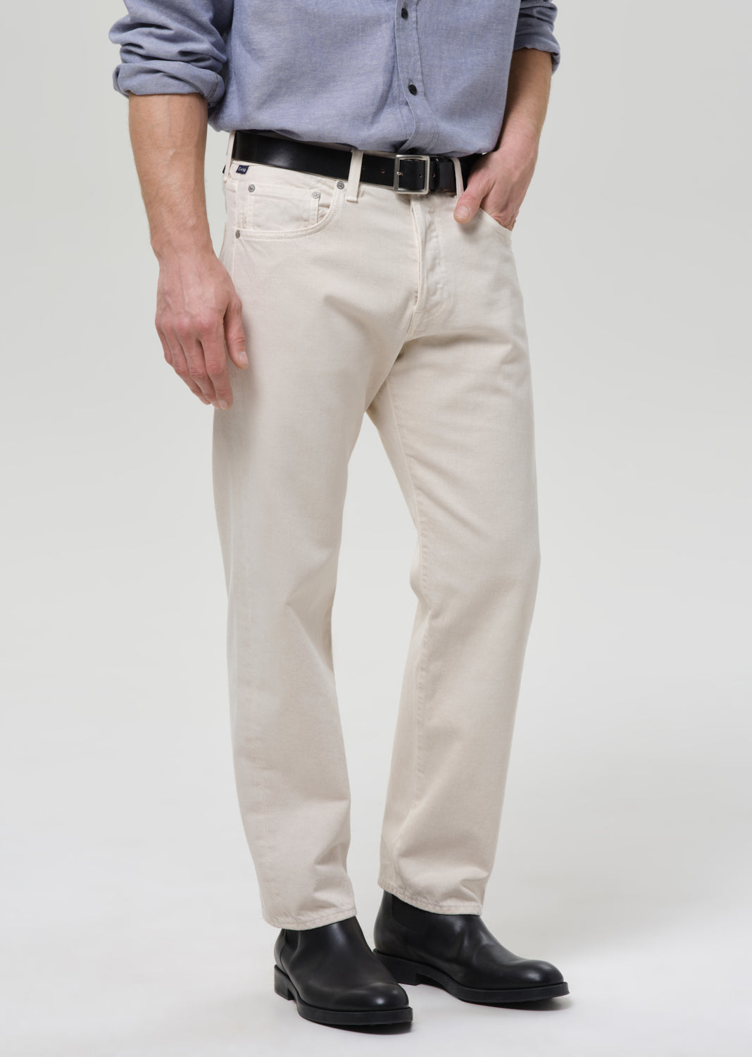 Person wearing beige pants grey a plain background