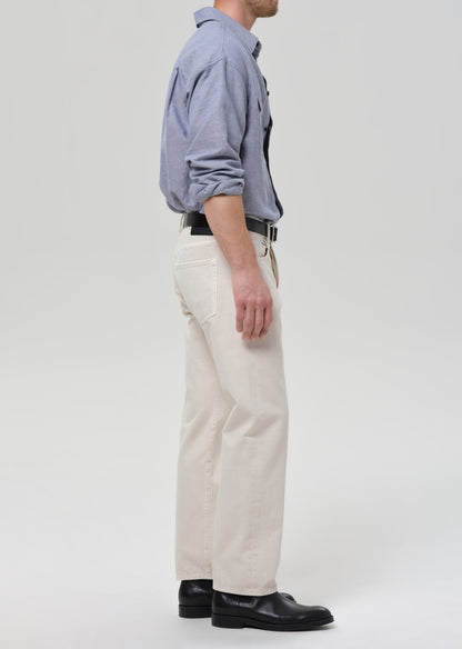 Person wearing a blue shirt, white pants, and black shoes on a grey background
