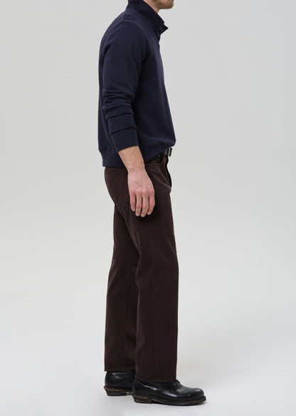 Person wearing a navy sweater and brown pants on a grey background