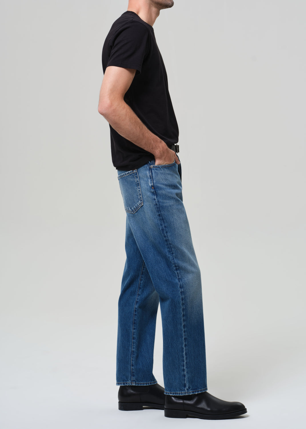 Person wearing blue jeans and a black shirt on a plain background