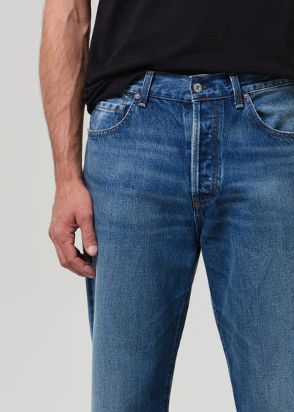 Blue jeans worn by a person on a plain background