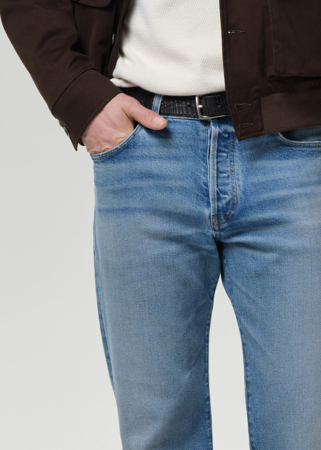 Person wearing blue jeans with a grey background.