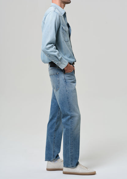Person wearing a light blue denim shirt and jeans on a white background