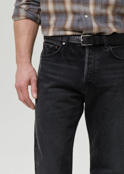 Person wearing black jeans and a plaid shirt on a grey background
