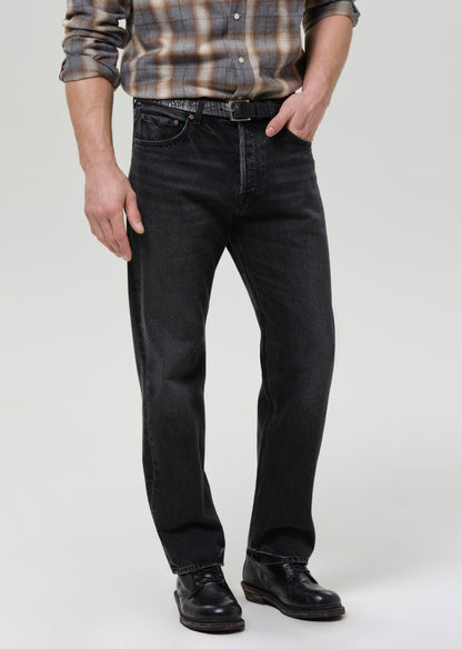 Person wearing black jeans and a plaid shirt on a grey background