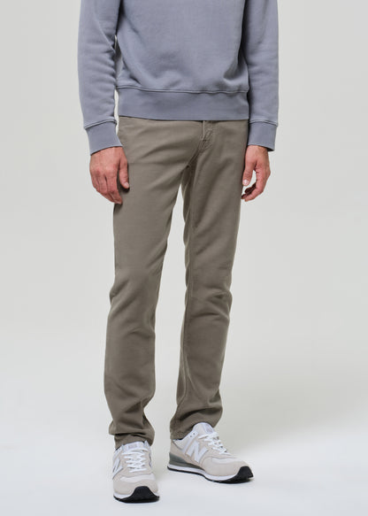Person wearing a gray sweatshirt and green pants on a grey background