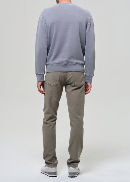 Person wearing a gray sweatshirt and green pants on a grey background