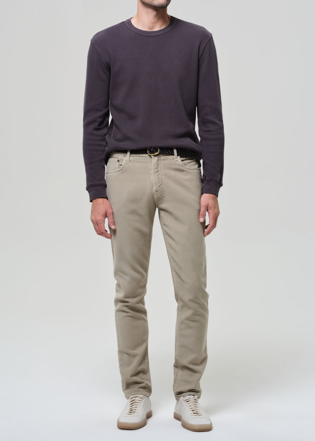 Man wearing a dark sweater and beige pants on a white background