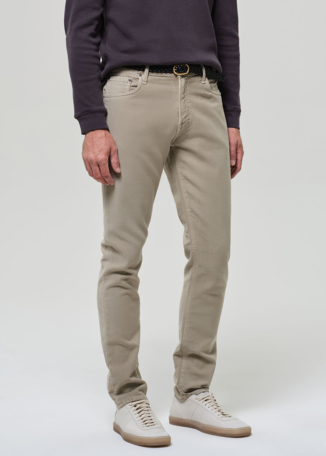 Person wearing beige pants and a dark shirt on a grey background