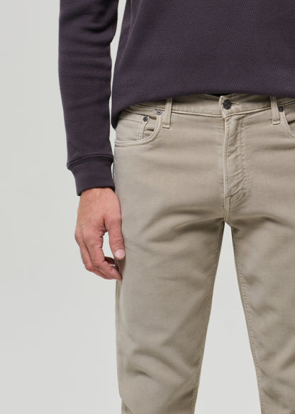 Person wearing beige pants and a dark long-sleeve shirt on a light gray background