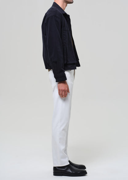 Person wearing a dark jacket, white pants, and black shoes on a plain background