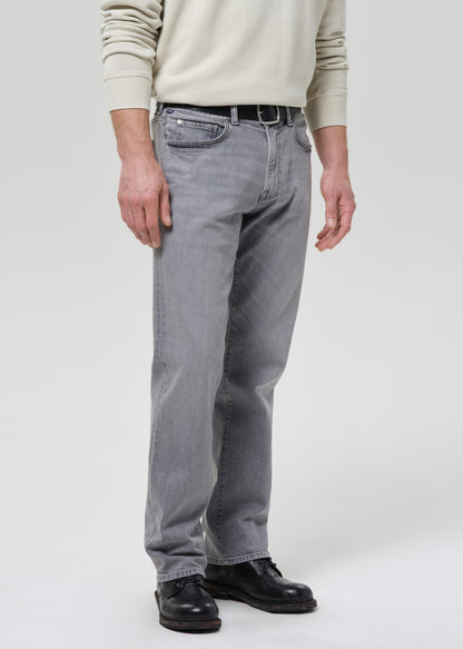 Person wearing grey jeans and a beige sweater on a grey background