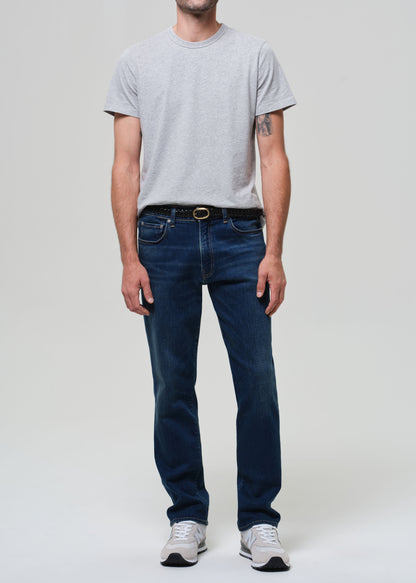 Person wearing a gray t-shirt and dark blue jeans on a plain background