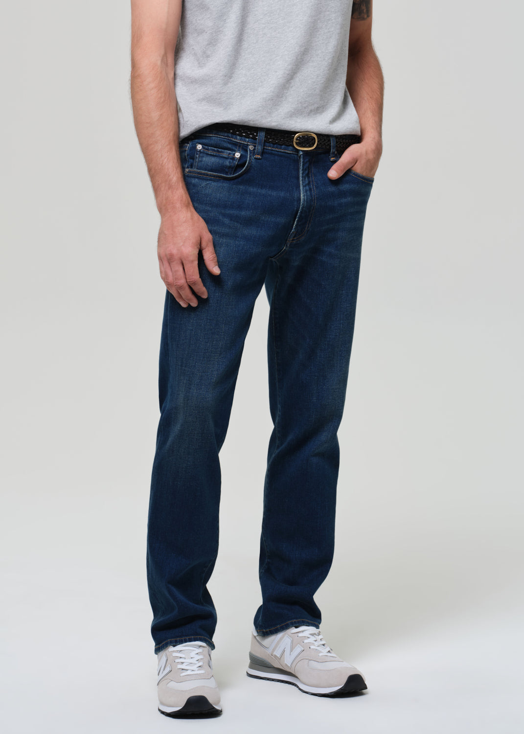 Person wearing blue jeans and a gray shirt on a white background