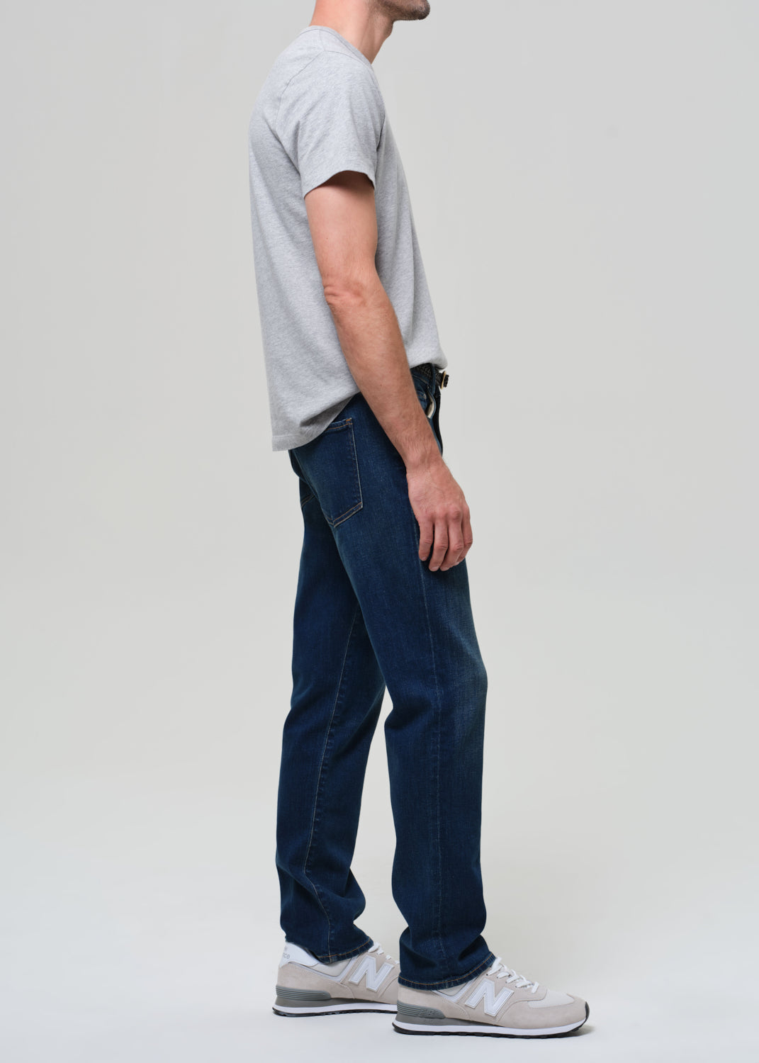 Person wearing a gray t-shirt and blue jeans on a plain background