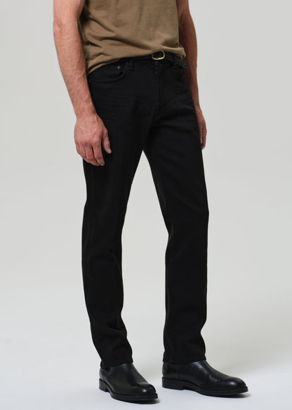 Person wearing black pants and a brown shirt on a plain background