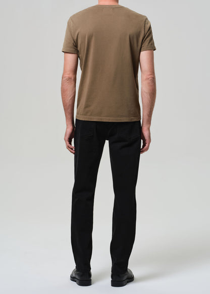 Person wearing a brown t-shirt and black pants on a white background