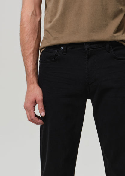 Person wearing black jeans and a brown shirt on a light gray background