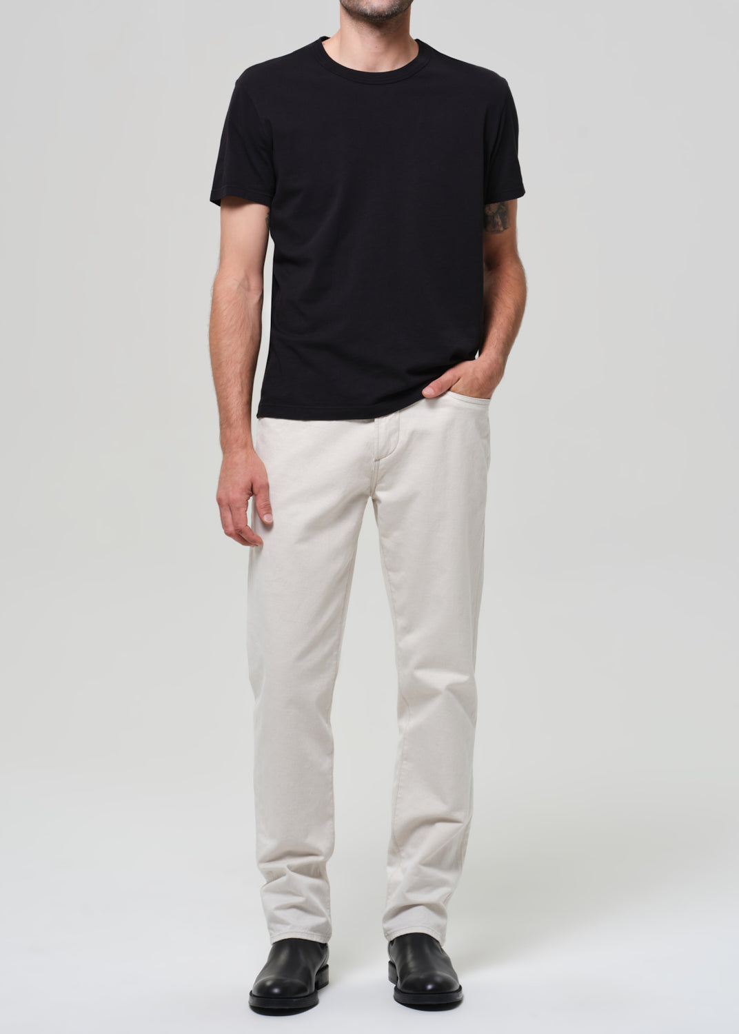 Person wearing a black t-shirt and white pants on a plain background