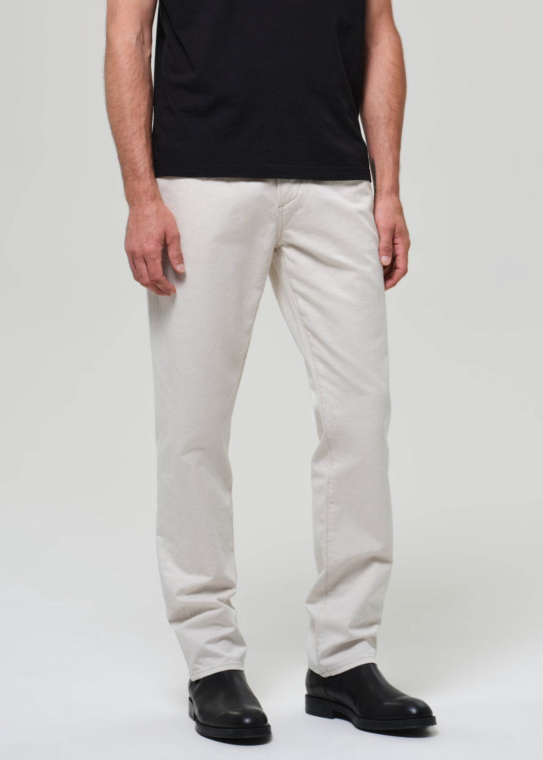 Person wearing white pants and black shoes on a plain background