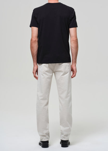 Person wearing a black t-shirt and light-colored pants on a white background