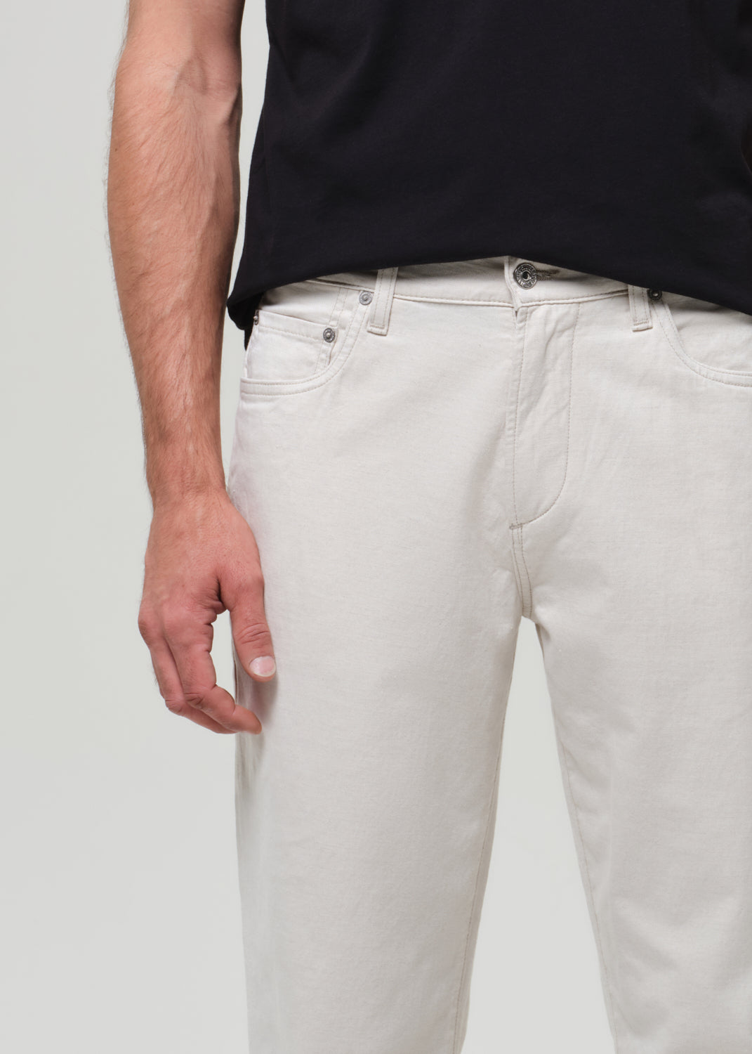 Person wearing light neutral pant and a black shirt on a plain background