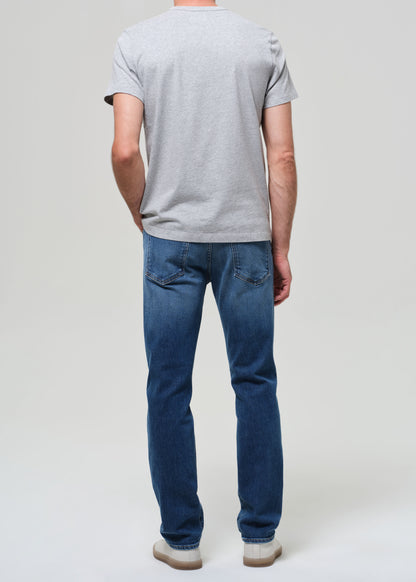 Person wearing blue jeans and a gray t-shirt on a plain background