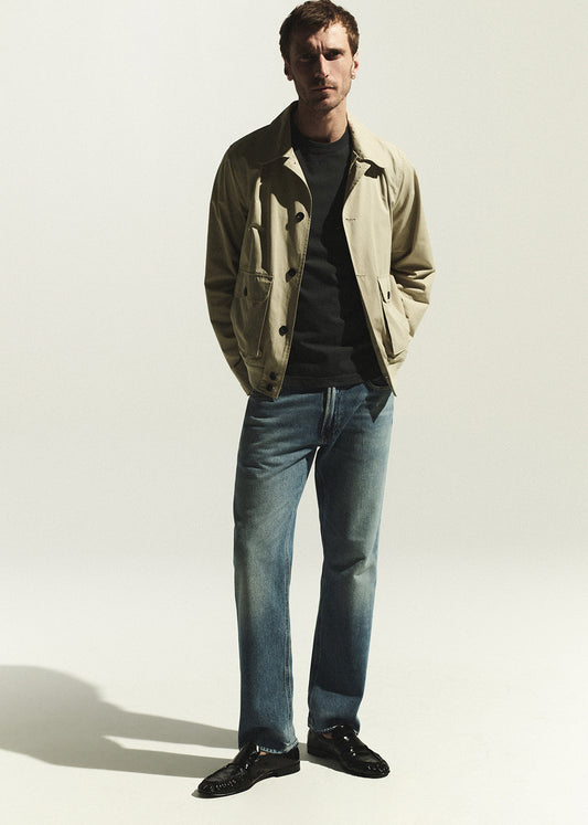 Man wearing a beige jacket and blue jeans 