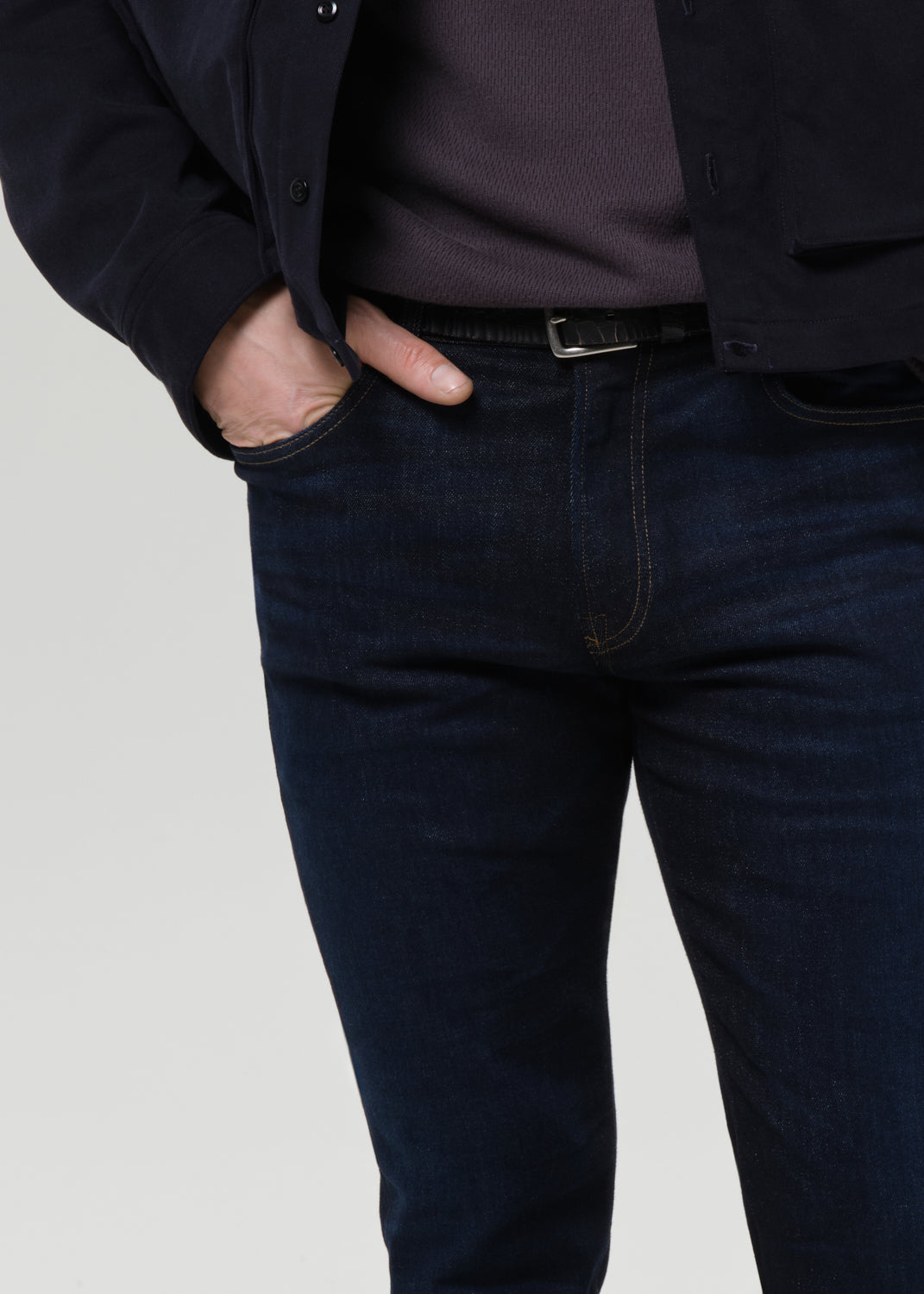 Close-up of dark indigo straight leg jeans on a grey background.