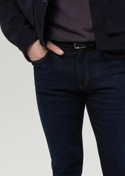 Close-up of dark indigo straight leg jeans on a grey background.