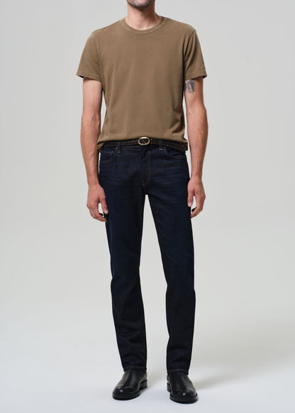 Person wearing a brown t-shirt and black jeans on a plain background