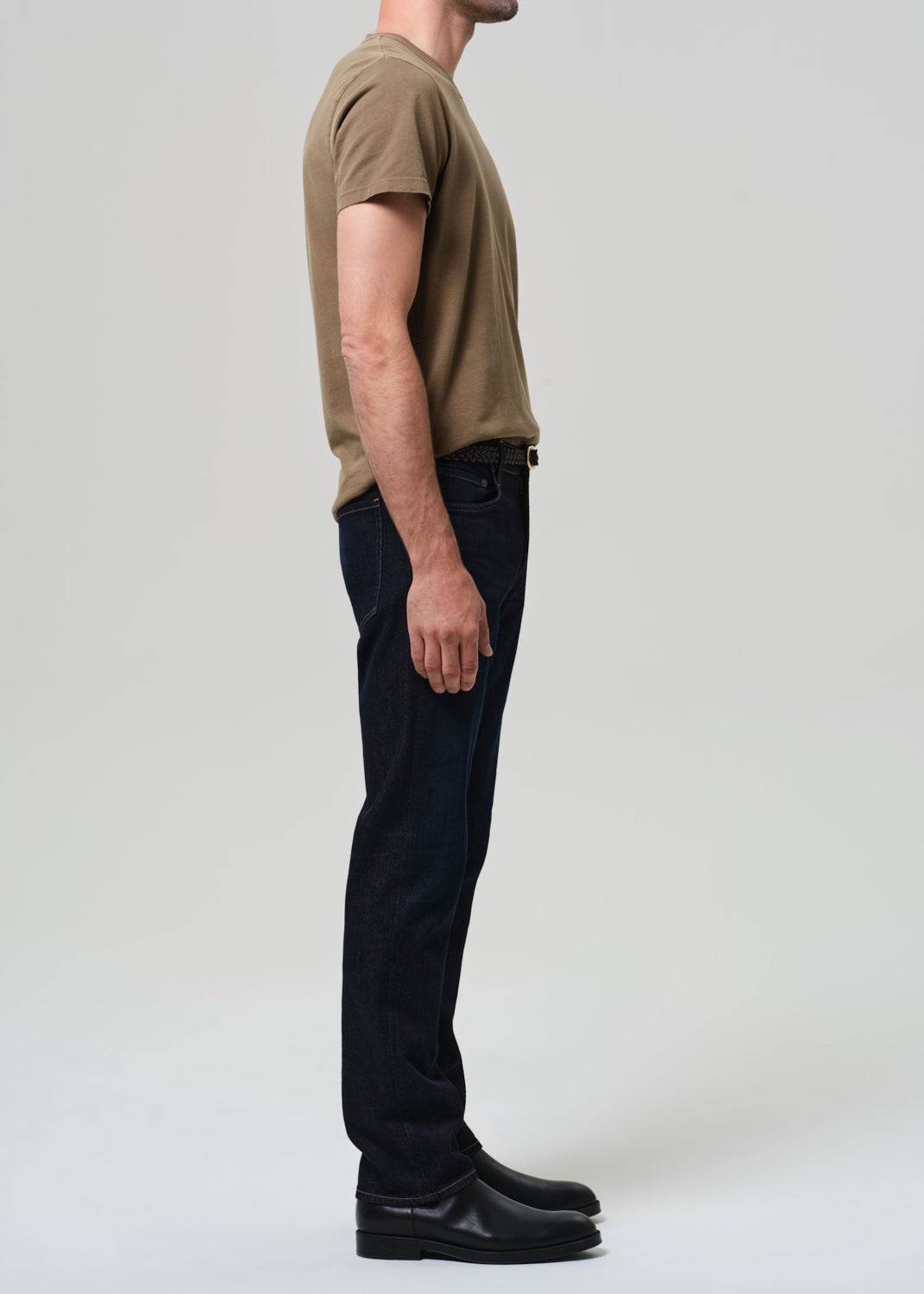 Person wearing a brown t-shirt and black pants on a plain background