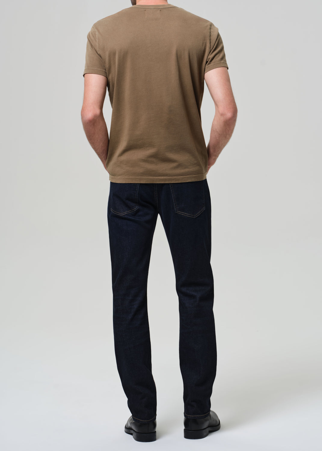 Person wearing a brown t-shirt and black pants on a white background