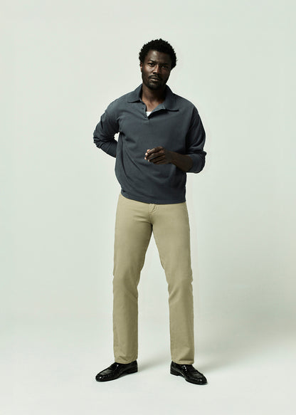 Man wearing a polo shirt and beige pants on a grey background
