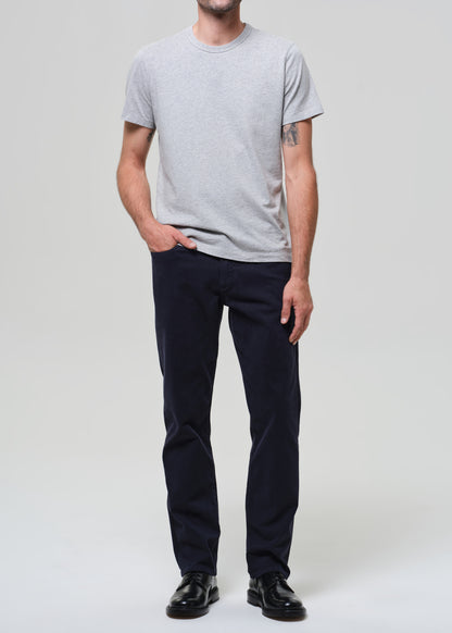 Person wearing a gray t-shirt and dark navy pants on a grey background