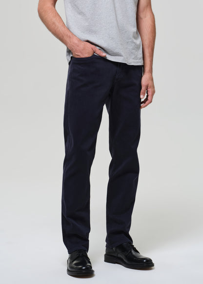 Person wearing a gray t-shirt and dark navy pants on a grey background