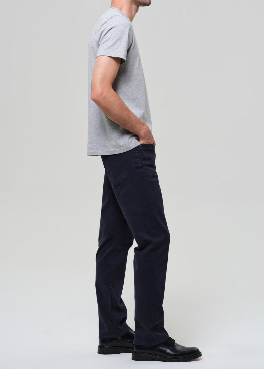 Person wearing a gray t-shirt and dark navy pants on a grey background